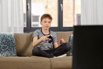 Image showing boy with remote control watching tv at home