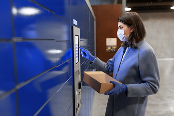 Image showing woman in mask with box at parcel machine