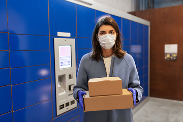 Image showing woman in mask with boxes at parcel machine