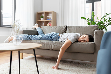 Image showing bored or lazy young woman lying on sofa at home