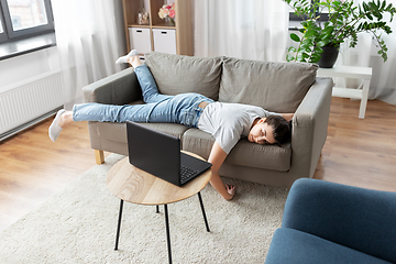 Image showing bored woman with laptop lying on sofa at home