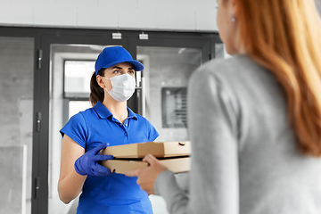 Image showing delivery girl in mask giving pizza boxes to woman