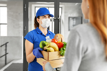 Image showing delivery girl in mask giving box of food to woman