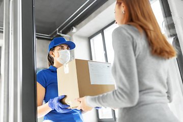 Image showing delivery girl in face mask giving parcel to woman