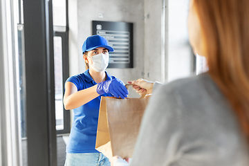 Image showing delivery girl in mask giving paper bag to customer