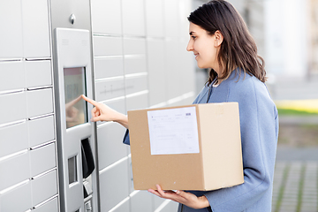 Image showing smiling woman with box at automated parcel machine