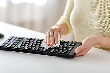 Image showing close up of woman cleaning keyboard with tissue