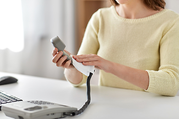 Image showing close up of woman cleaning desk phone with tissue