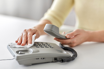 Image showing close up of woman cleaning desk phone with tissue