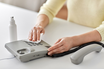 Image showing close up of woman cleaning desk phone with tissue