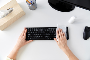 Image showing close up of woman cleaning keyboard with tissue