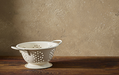 Image showing white metal strainer on wooden shelf