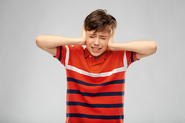 Image showing boy closing ears with hands over grey background