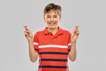 Image showing smiling boy in t-shirt holding fingers crossed