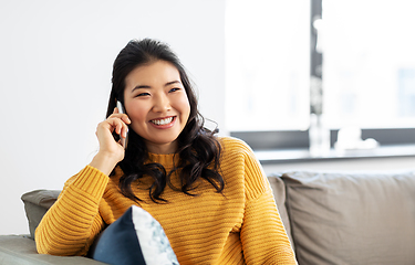 Image showing smiling asian woman calling on smartphone at home