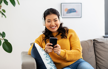 Image showing asian woman with headphones and smartphone at home