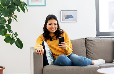 Image showing asian woman with earphones and smartphone at home