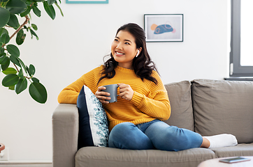 Image showing woman in earphones listening to music at home