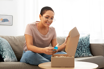 Image showing african american woman opening parcel box at home