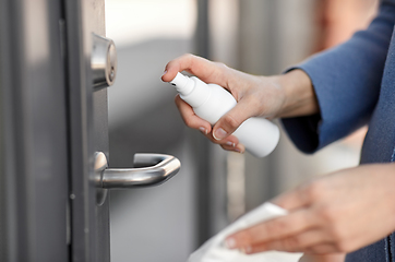 Image showing hand cleaning door handle with disinfectant spray