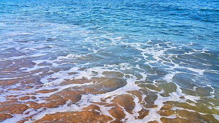 Image showing Sea water with white foam on the coastal sand