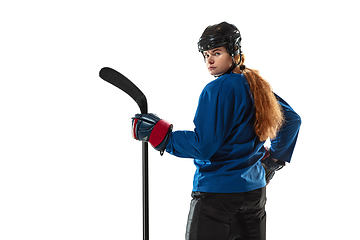 Image showing Young female hockey player with the stick on ice court and white background