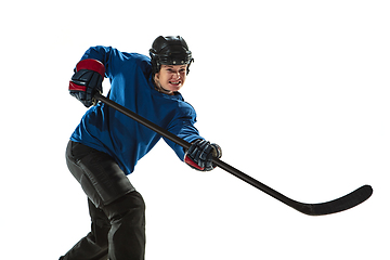 Image showing Young female hockey player with the stick on ice court and white background