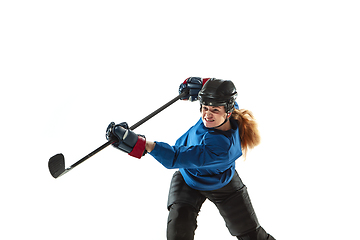 Image showing Young female hockey player with the stick on ice court and white background