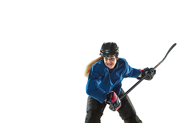 Image showing Young female hockey player with the stick on ice court and white background