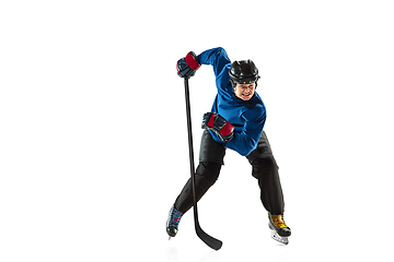 Image showing Young female hockey player with the stick on ice court and white background