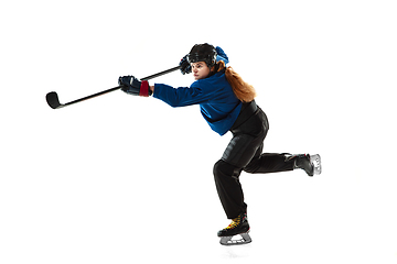 Image showing Young female hockey player with the stick on ice court and white background