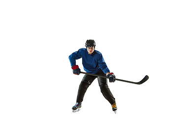 Image showing Young female hockey player with the stick on ice court and white background