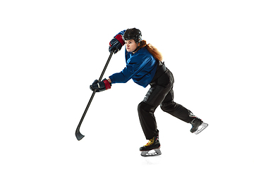 Image showing Young female hockey player with the stick on ice court and white background