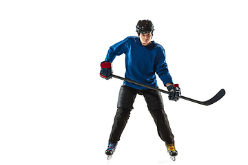 Image showing Young female hockey player with the stick on ice court and white background