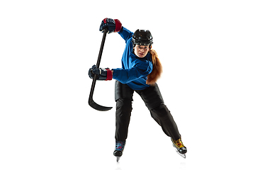 Image showing Young female hockey player with the stick on ice court and white background