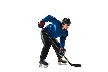 Image showing Young female hockey player with the stick on ice court and white background