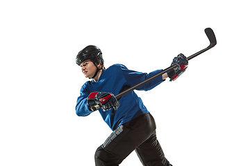 Image showing Young female hockey player with the stick on ice court and white background