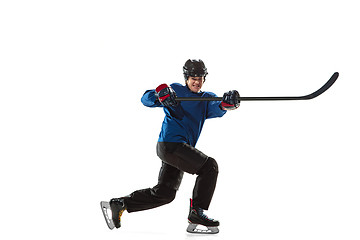 Image showing Young female hockey player with the stick on ice court and white background