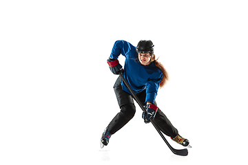 Image showing Young female hockey player with the stick on ice court and white background