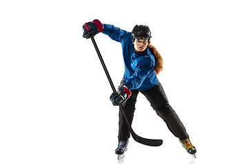 Image showing Young female hockey player with the stick on ice court and white background