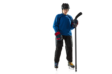 Image showing Young female hockey player with the stick on ice court and white background