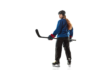 Image showing Young female hockey player with the stick on ice court and white background