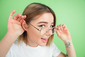 Image showing Caucasian young woman\'s portrait on green studio background