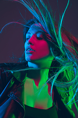 Image showing Beautiful woman\'s portrait with blowing hair on dark studio background in colorful neon light