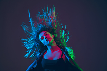 Image showing Beautiful woman\'s portrait with blowing hair on dark studio background in colorful neon light