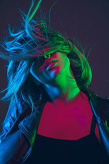 Image showing Beautiful woman\'s portrait with blowing hair on dark studio background in colorful neon light