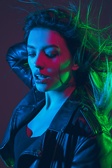 Image showing Beautiful woman\'s portrait with blowing hair on dark studio background in colorful neon light