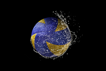 Image showing Volleyball ball flying in water drops and splashes isolated on black background