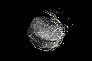 Image showing Puck flying in water drops and splashes isolated on black background