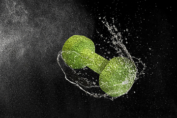 Image showing Dumbbell flying in water drops and splashes isolated on black background